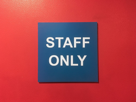 Blue label "staff only" on red backgroundの写真素材