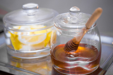 Honey and lemon in a glassware on a stainless steel tray backgroundの写真素材
