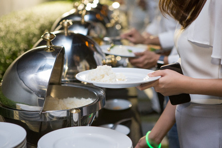 Women are scooping food from chafing dishes on the table at the luxury banquetの写真素材