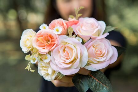 Woman holding a bouquet of roses on a blurred backgroundの写真素材