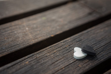 Little white and black heart on an old wooden table with sunlight background