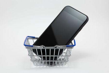 Smartphone in Steel shopping basket on white background