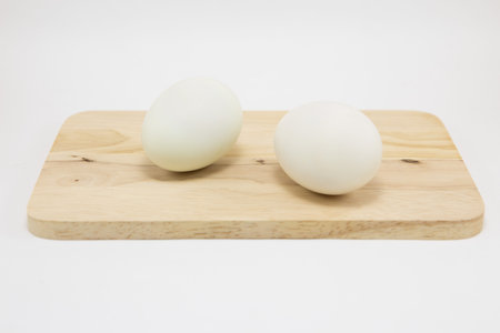 Fresh white eggs on a wooden cutting board on white backgroundの写真素材