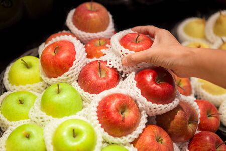 Woman hand holding an apple on the shelves in the supermarketの写真素材