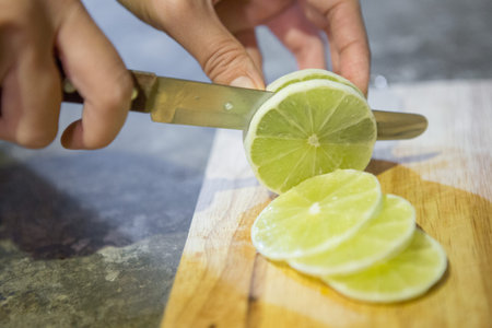 Female hand is slicing lemon on a cutting board