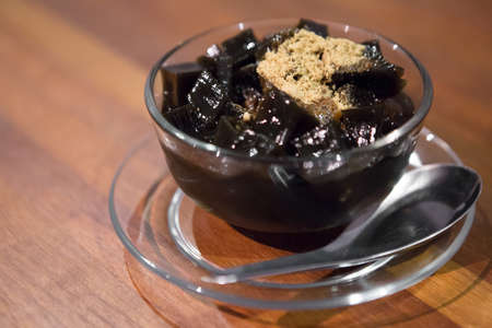 Close up Black grass jelly in a clear cup on a wooden tableの写真素材