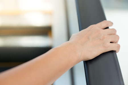 woman's hand is holding the rail of the escalatorの写真素材