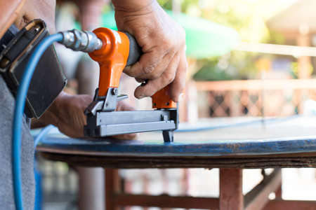 hand of a worker is using a nail gun on a piece of work carefullyの写真素材