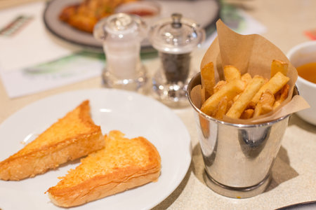French fries in a bucket of steel and toast on the table