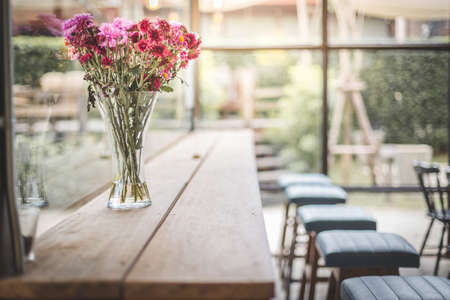 Beautiful flowers in the vase on the counter in the cafe with warm lightの写真素材