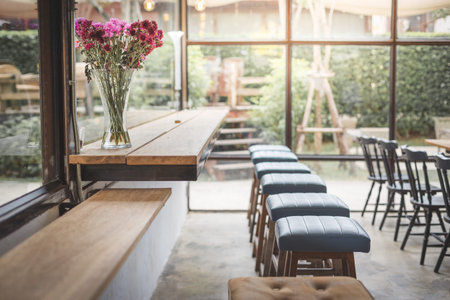 Beautiful flowers in the vase on the counter in the cafe with warm lightの写真素材