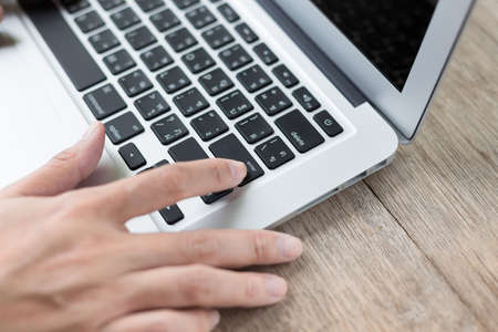 Woman hand pressing a Enter button on a laptop on the wood table backgroundの写真素材