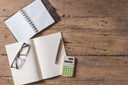 Top view of Pen, notebook, glasses, calculator,  smartphone on the wooden table and copy spaceの写真素材