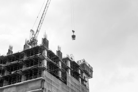Black and white of Crane on the building under construction on blue sky and cloud background