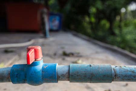 Old Red faucet on blue plumbing on blurred backgroundの写真素材