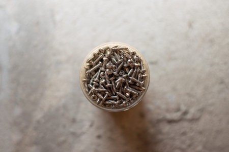 Many screws in the container on a concrete background and copy space