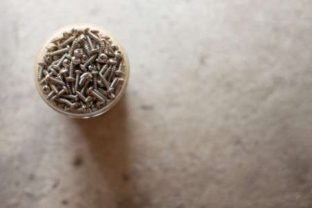Many screws in the container on a concrete background and copy spaceの写真素材
