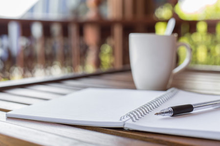 Selective focus of Pen, notebook , coffee cup on the wooden table with warm light and copy space