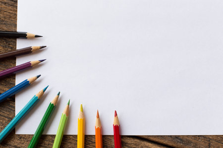 colorful colored pencil and white paper on wooden background