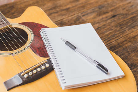 Selective focus of Acoustic guitar , Notebook paper and pen on wood background and copy spaceの写真素材