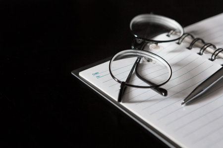 Selective focus of Pen, notebook, glasses, on black background and copy space