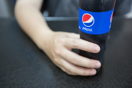 Bangkok Thailand , July 14 , 2019 : Selective focus of Hands holding a Pepsi bottle pour in stainless steel glass on the tableのeditorial素材