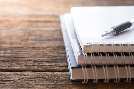 Selective focus of Pen, notebook on the wooden table and copy space with sunlight