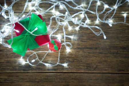 Top view of Red gift box with green ribbon and LED lights decorated on wood and bokeh light backgroundの写真素材