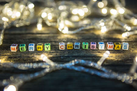 Selective focus of Colorful Alphabet beads "Merry Christmas" and LED lights on wooden floor backgroundの写真素材
