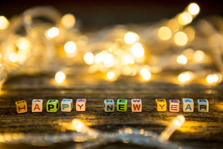 Selective focus of Colorful Alphabet beads "Happy New year" and LED lights on wooden floor backgroundの写真素材