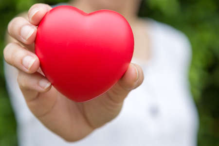 Selective focus of A woman with a heart shaped ball in her hand on blurred backgroundの写真素材