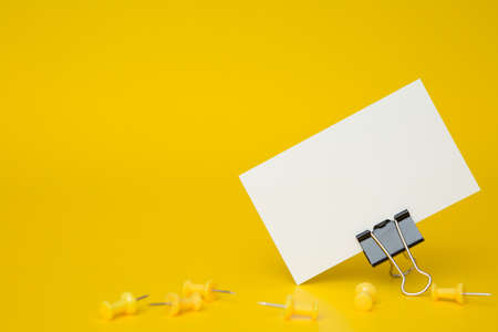 Close up of Business card and yellow pins on a yellow backgroundの写真素材