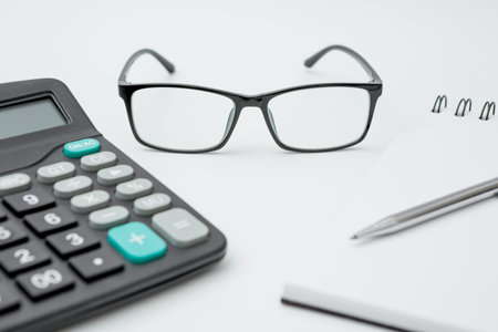 Notebooks, calculator, pens, glasses on white background and copy space