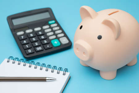 Notebooks, Piggy bank, calculator, pens on blue background and copy spaceの写真素材