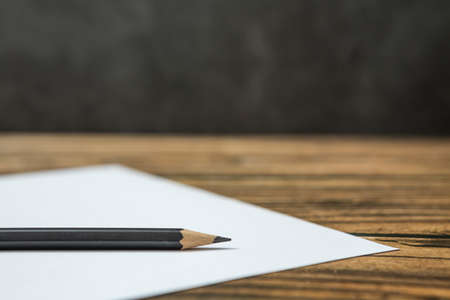 Selective focus of Black pencil on white paper on a wooden table and copy spaceの写真素材