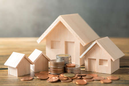 Model house, coins stack on wooden desks and loft walls with sunlight and copy space for money saving conceptの写真素材