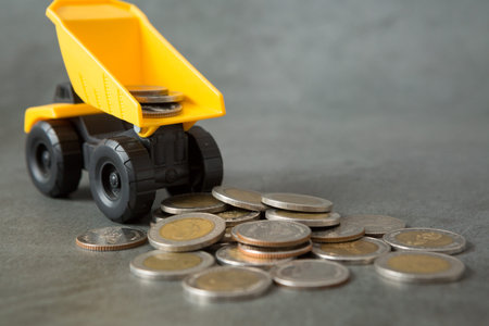 Dump truck, coins stack on loft walls with sunlight and copy space for money saving concept
