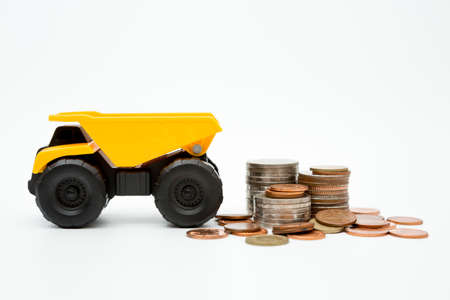 Dump truck, coins stack on white background for money saving conceptの写真素材