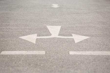 Selective focus of Crossroad arrow symbol on the roadの写真素材