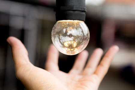 Selective focus of Hand holding a light bulb on blurred background for Clean energy for environment and copy spaceの写真素材