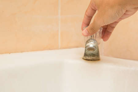 Hand holding to close the old and dirty faucet on the wash basin and copy spaceの写真素材