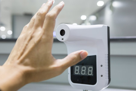 Infrared thermometer on blurred background. People must measure their temperature before entering the building or using any services. corona virus and covid 19 concept.の写真素材