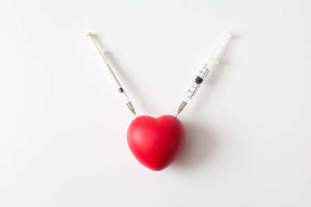 Heart was stabbed by a syringe on white background and copy space for health care conceptの写真素材