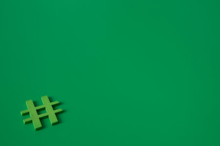 Green wooden symbol Hashtag "#" on green background and copy space for social media educational conceptの写真素材