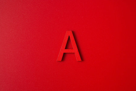 Red wooden english letters A on red background and copy space for educational and graphic concept