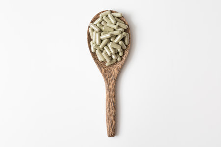 Many pill capsules in a wooden spoon on white background and copy space for health care conceptの写真素材