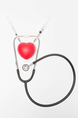 Heart was stabbed by a syringe and stethoscope on a white background and copy space for health care conceptの写真素材