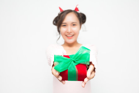 Selective focus of woman hand holding red gift box on white background. Cute Asian woman smiling and cheerful on Christmas and New Year's Day.の写真素材