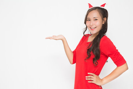 Beautiful Asian woman wearing small Santa hat and wearing red dress on white background. Cute Asian...