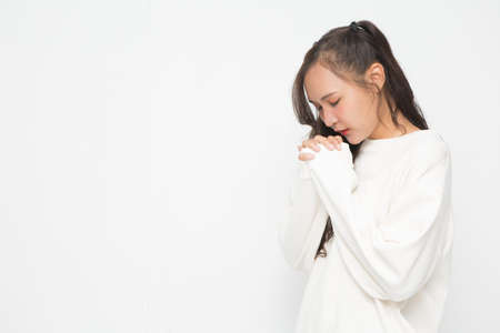 Beautiful Asian woman wearing white sweater praying on white background.の写真素材